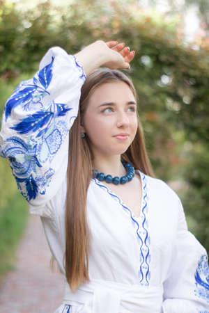 ukrainian blonde girl in national blue dress - embroidered shirt. young woman patriot. outdoors photo of charming female.の写真素材