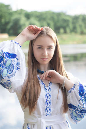 Portrait of young woman wearing blue national traditional embroidered shirt. pretty girl outdoor dressed in patriotic clothes.の写真素材