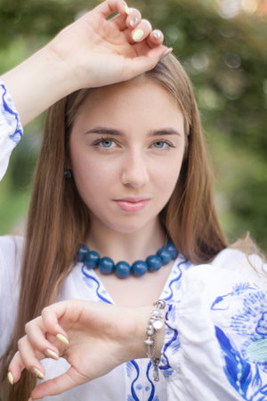Portrait of young woman wearing blue national traditional embroidered shirt. pretty girl outdoor dressed in patriotic clothes.の写真素材