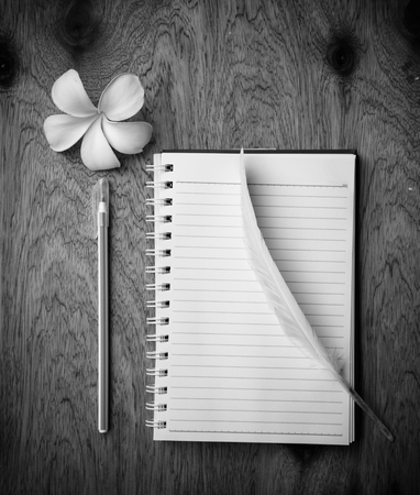 blank notebook with White Feather  and pen on wooden table, black and white conceptの写真素材