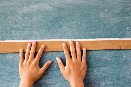 hands draw on the blackboard with a rulerの写真素材