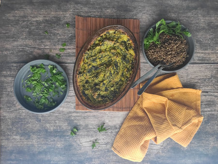 A painted vegetarian meal with baked mashed potatoes and spinach, lentils and a bunch of persil.