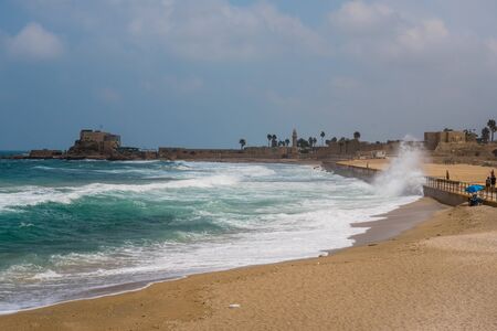 Photo of surf on beach with sand and Ceasaria castle bay, Israel