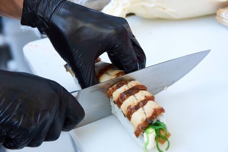Cook hands making eel sushi roll closeup photoの写真素材