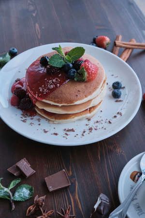 Plate of fresh pancakes piled with fresh fruit and covered in syrup / Daylight shot