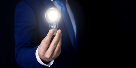 businessman holds shining light bulb, symbol of ideaの写真素材