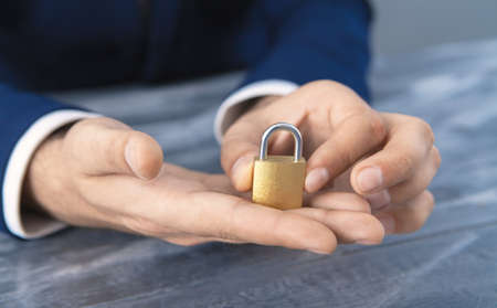 young businessman holding padlock in his hands; security business conceptの写真素材