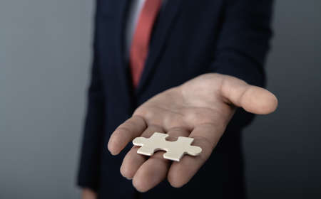 businessman holds a piece of the puzzle in his hand; business concept