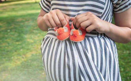 pregnant woman holding baby shoes