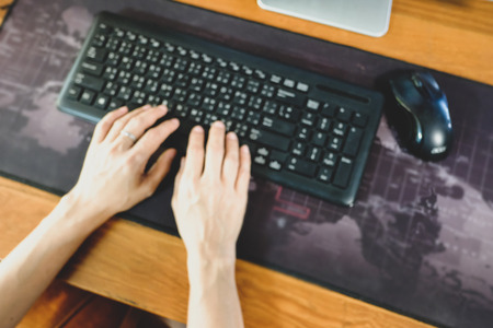 Woman sitting typing keyboard, blurred.の写真素材