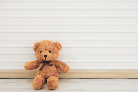 Brown bear sitting against a white wall I sent everyone encouragement.の写真素材
