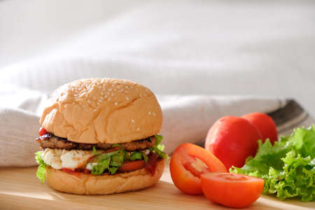 Burgers with cheese, salads and vegetables on a white background wooden board.の写真素材