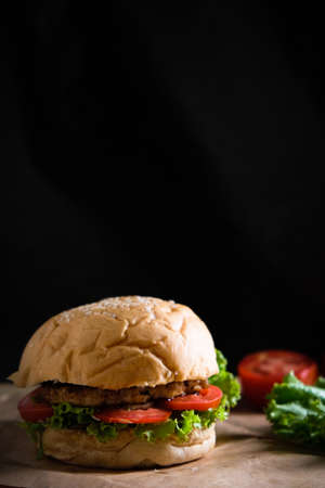 Burgers with cheese, salads and vegetables on a black background wooden board.の写真素材