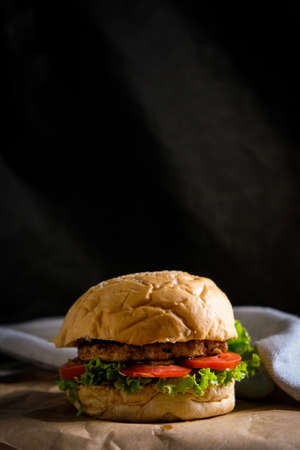 Burgers with cheese, salads and vegetables on a black background wooden board.の写真素材