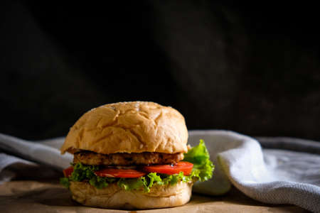 Burgers with cheese, salads and vegetables on a black background wooden board.の写真素材
