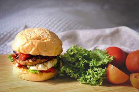 Burgers with cheese, salads and vegetables on a white background wooden board.の写真素材