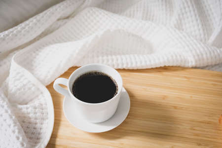 Coffee bread in a white cup placed on the bed, white linen during the morning, fresh airの写真素材