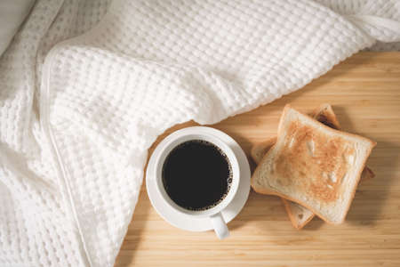 Coffee bread in a white cup placed on the bed, white linen during the morning, fresh airの写真素材
