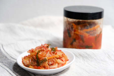 Kimchi is placed in a white plate with a fork on its side.の写真素材
