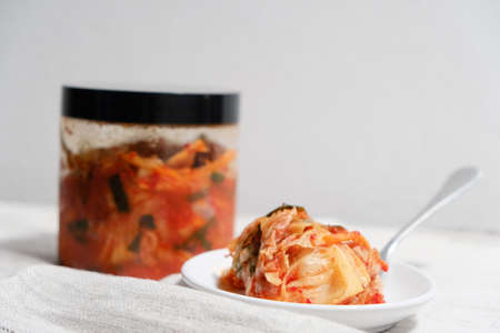 Kimchi is placed in a white plate with a fork on its side.の写真素材