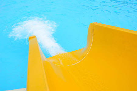 yellow plastic slider in front of swimming pool の写真素材