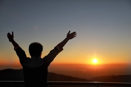 Happy Businessman show hand up for successful at beautiful sunset time, Silhouette the man hand  at sunset,Silhouette of Man Raising His Hands or Open arms when sunset.の写真素材