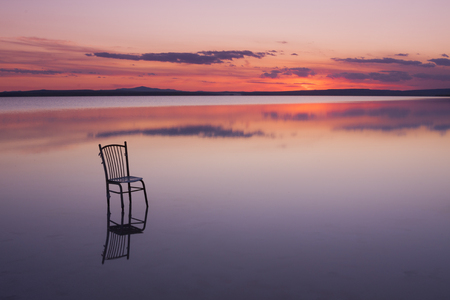 chair on a lake at sunset with beautiful coloursの写真素材