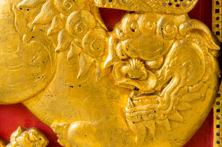 Gold Chinese lion on the red wood doorの写真素材