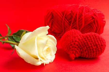 Cream rose with red heart crochet on red background. Selective focus.の写真素材
