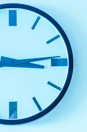 Close up of modern clock on the white wall. Blue tone.の写真素材