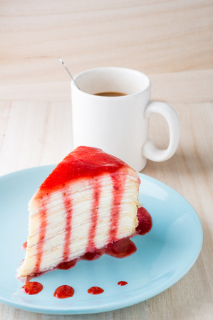 Mille crepe cake with strawberry sauce and coffee on wooden background. Selective focusの写真素材