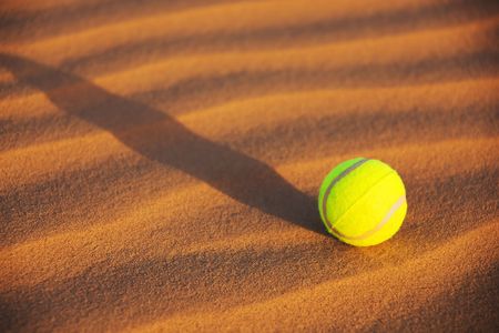a yellow tennis ball in desert sandの写真素材