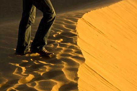 detail of man's leg walking on a sand dune