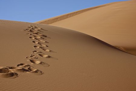 footprints on desert sand dune with blue skyの写真素材