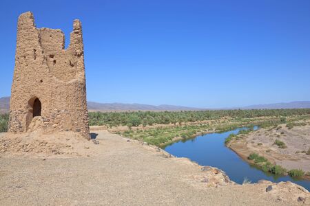 Clay ruin with date palm oassis, river and a cloudless blue skyの写真素材