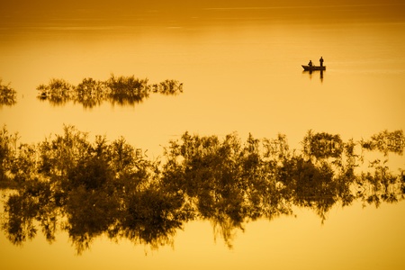 A fishing boat with two men on a lake in orange light.  With copy space. の写真素材