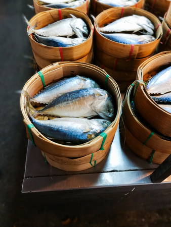 Steamed mackerel fish in bamboo baskets on sale at a market in Thailand.
