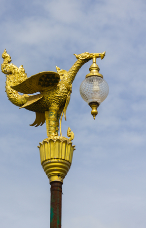 Golden swan statue with a lamp on blue sky and cloud background.の写真素材