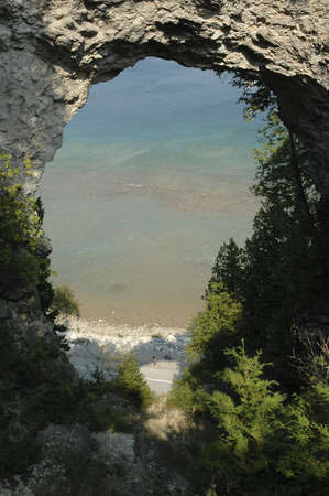A view of a lake through a natural stone archway.の写真素材