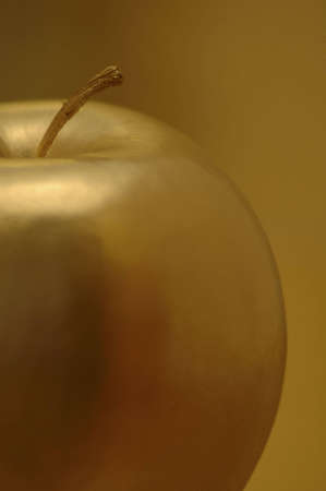 A golden apple against a golden background.の写真素材