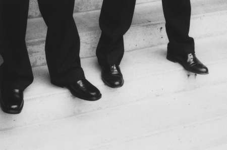 Two pairs of legs and feet waiting on steps.の写真素材