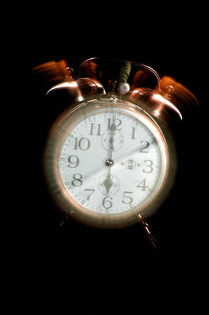 An old-fashioned alarm clock set to 6 a.m. The clock appears to be ringing.の写真素材