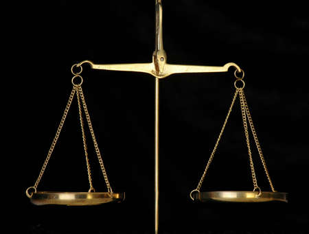 A golden balance scale against a black background.の写真素材