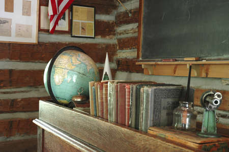 A teacher's desk and a chalkboard in an old-fashioned one-room schoolhouse.