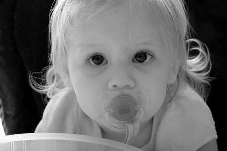 A black and white portrait of a  with a pacifier in her mouth.の写真素材