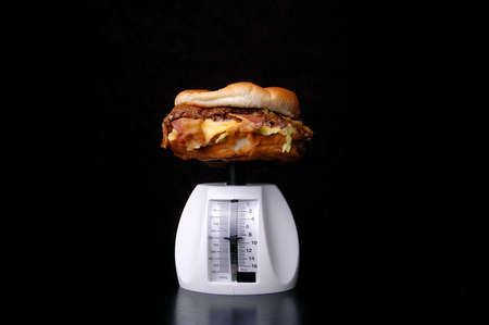 A hamburger on a food scale against a black background.の写真素材