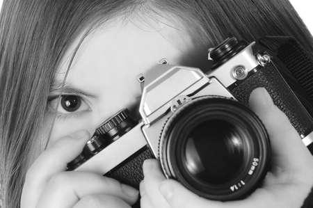 A woman positions a camera for a shot. One eye is visible. Black and white.