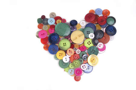 A heart formed with colorful buttons isolated against a white background.