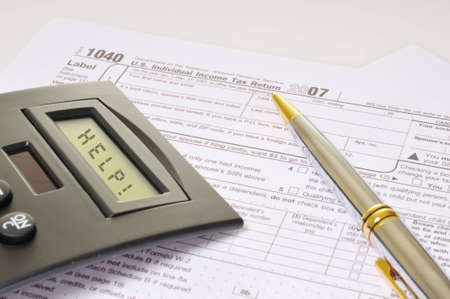 A caculator and a pen rest on federal tax forms. The calculator screen spells, 
