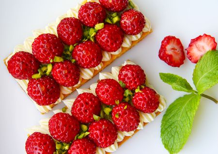 two fresh strawberry tarts with cream, pistachio and honeyの写真素材